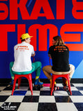 Two people sitting on red stools in front of a colorful wall with Skate Time text.