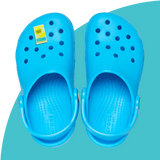 Blue croc shoes with Bjorn Qorn croc charm on blue background. 