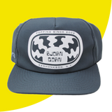 Gray cap with logo and text on a yellow background