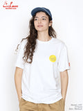 Person wearing a white t-shirt with a yellow logo and a blue cap on a plain background