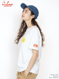 Woman wearing a white t-shirt with logos and a blue cap on a plain background