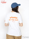 Person wearing a white t-shirt with 'Popped by the Sun' text, standing against a plain background.